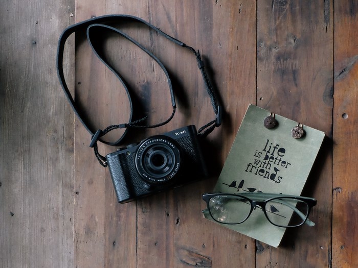 Fujifilm camera, notebook, and glasses on wood