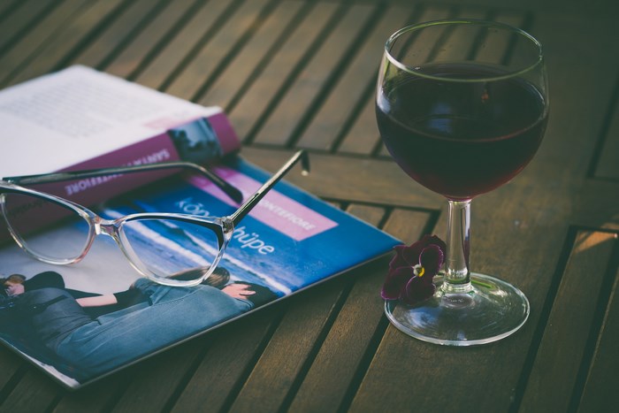 Wine glass, book, and glasses on a wooden table
