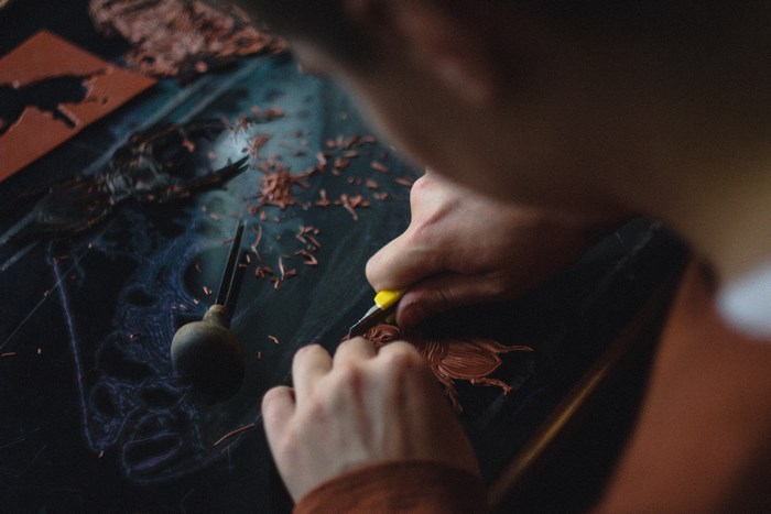 Man carving a beetle design on a dark surface