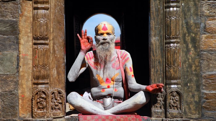 Painted Sadhu meditating in a temple doorway