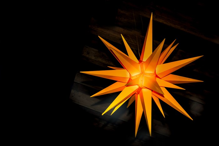 Orange Moravian star lantern against a dark background