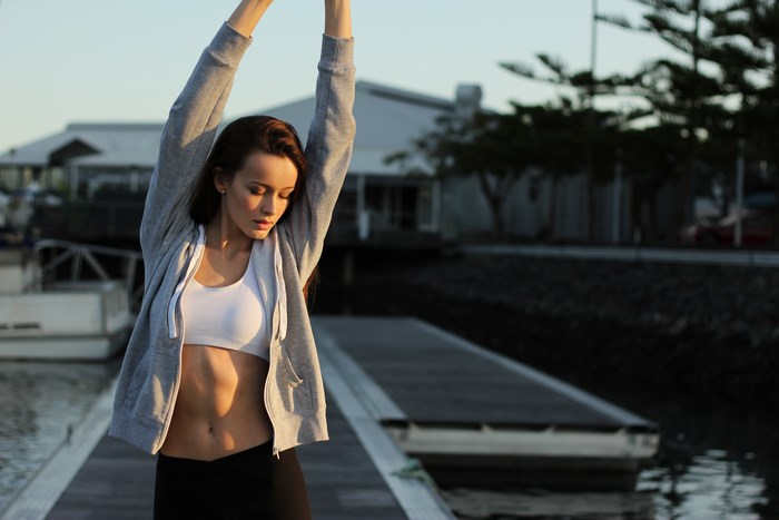 Woman in sportswear stretching by the water