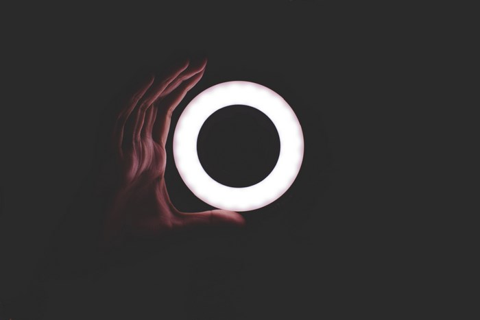 Hand holding a glowing ring light in the dark