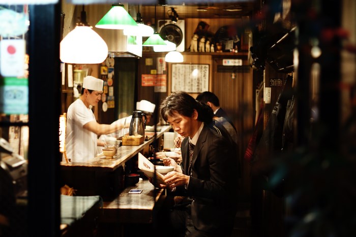 Man reading menu at a Japanese restaurant counter