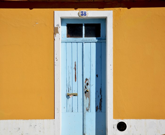 Weathered blue door with number 38 on orange wall