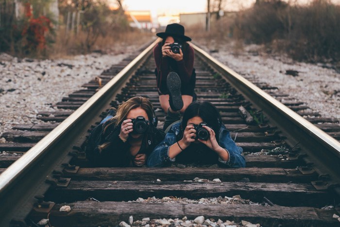 Three women with cameras on train tracks