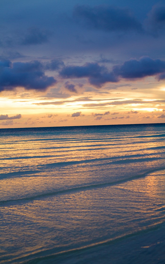Ocean waves at sunset with clouds