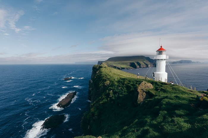 White lighthouse on a grassy cliff overlooking the ocean