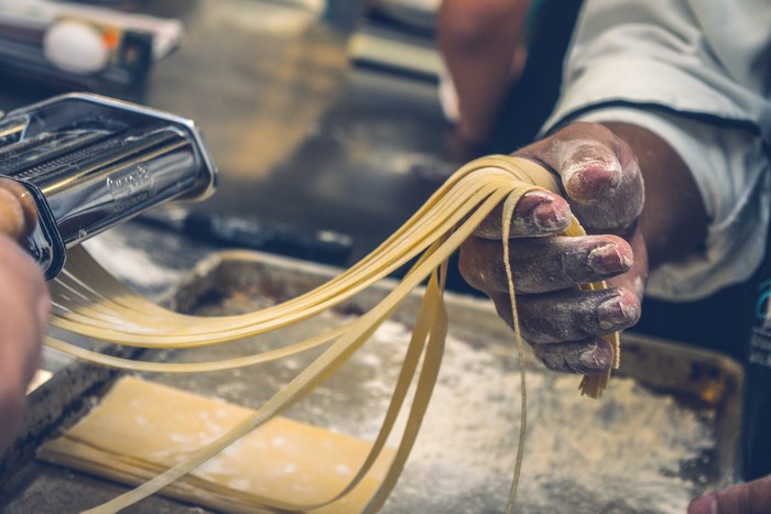 Chef making fresh pasta with a pasta maker