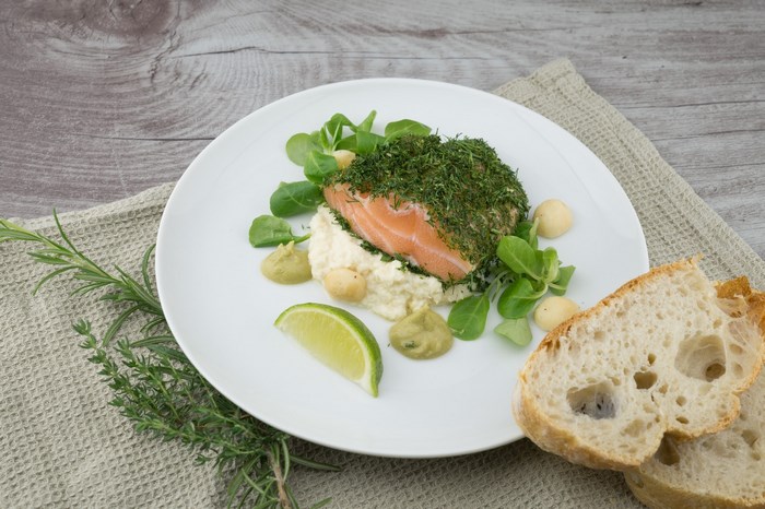 Salmon with herbs, lime, and bread on a plate
