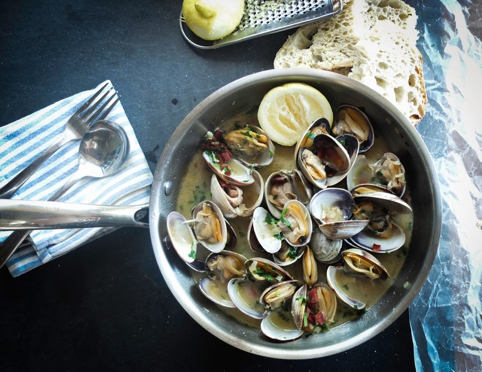 Seafood stew with clams, lemon, and bread in a pan