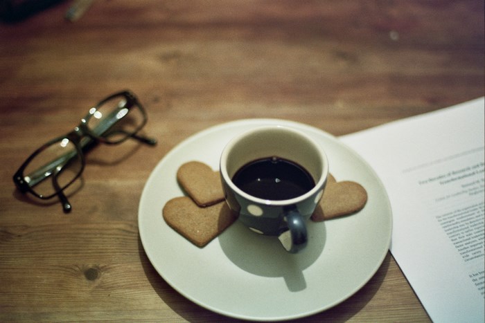 Coffee cup with heart cookies and glasses on a wooden table
