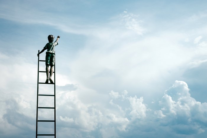 Boy on a ladder reaching for the sky