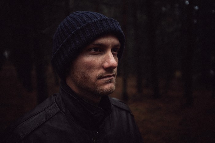 Man wearing a beanie and jacket in a forest