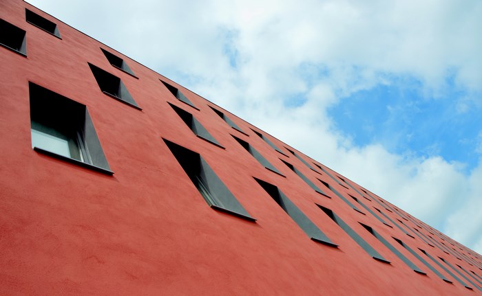 Red building facade with geometric windows against blue sky