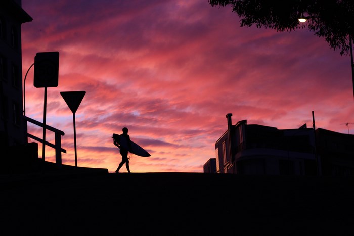 Surfer walking with surfboard at sunset in Australia
