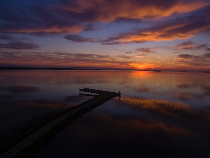 Sunrise over a calm bay with a pier
