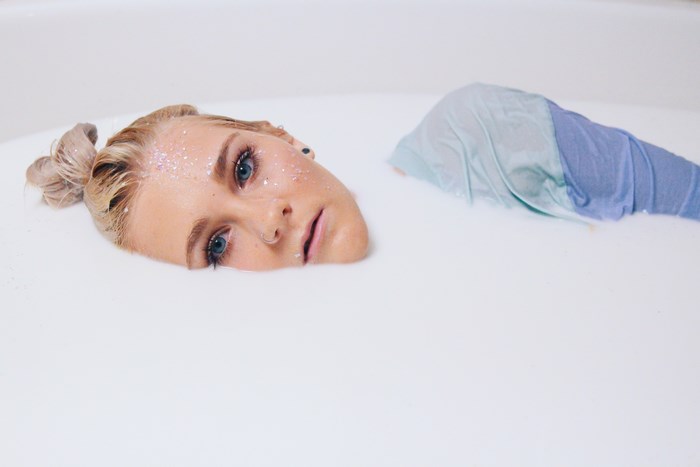 Blonde Woman Relaxing in Sparkling Milk Bath