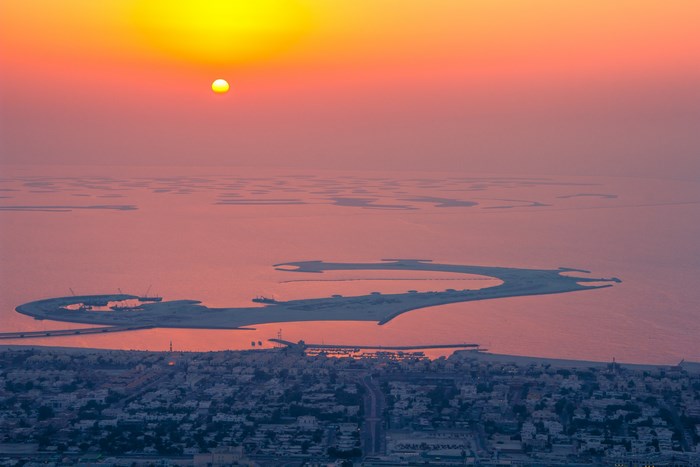Dubai islands at sunset with sun and haze