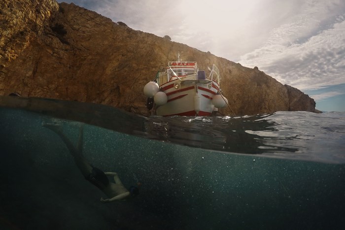 Boat taxi and diver near rocky cliff