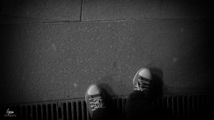 Converse shoes on pavement with grate