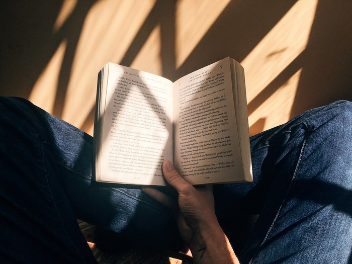 Person reading a book with sunlight and shadows