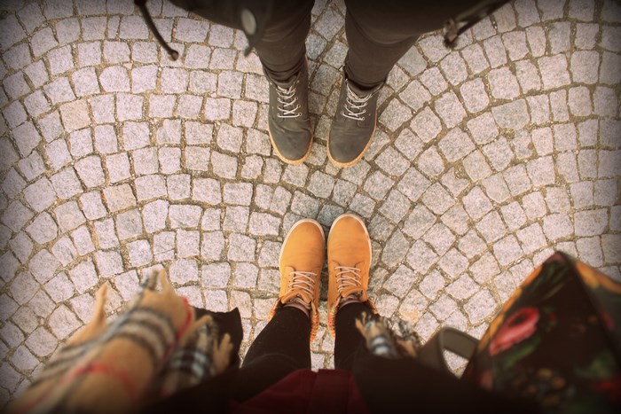 Two pairs of feet on a cobblestone sidewalk