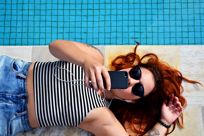 Woman with red hair taking a selfie by the pool