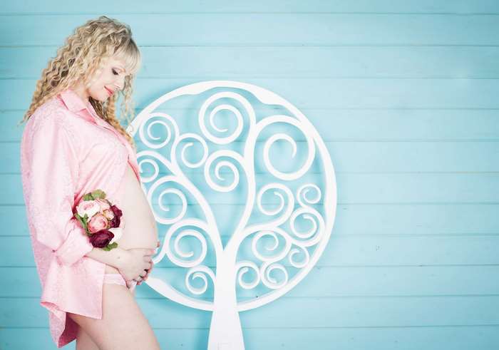 Pregnant woman in pink shirt holding flowers