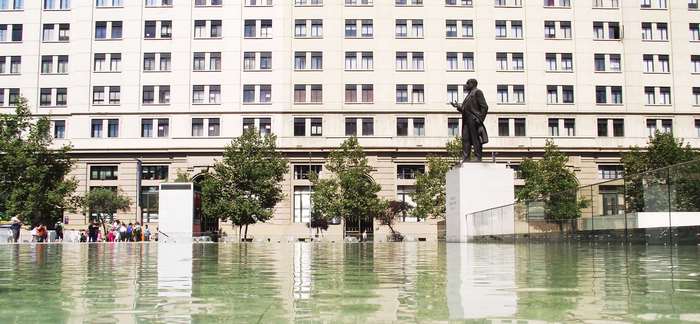 Statue in front of a large building with a fountain