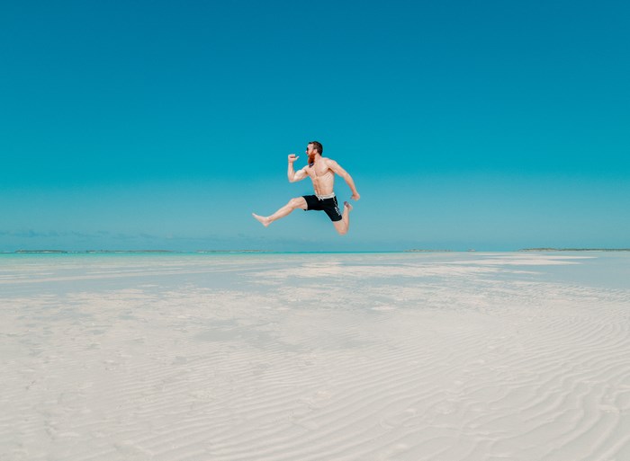 Man jumping on a tropical beach with blue sky