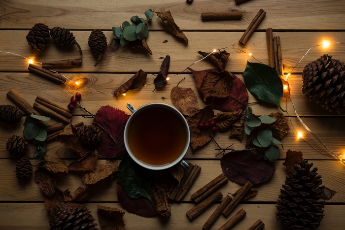 Autumn flatlay with tea, pine cones, and fairy lights