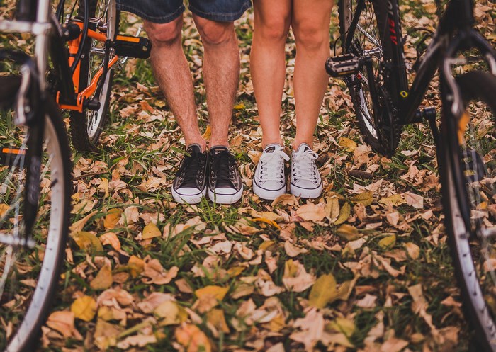 Couple's feet with bicycles in autumn leaves