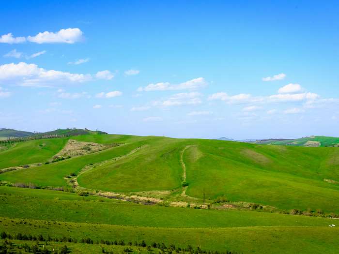 Green rolling hills under a blue sky with clouds