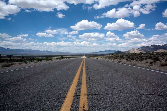 Desert road with double yellow lines and mountains