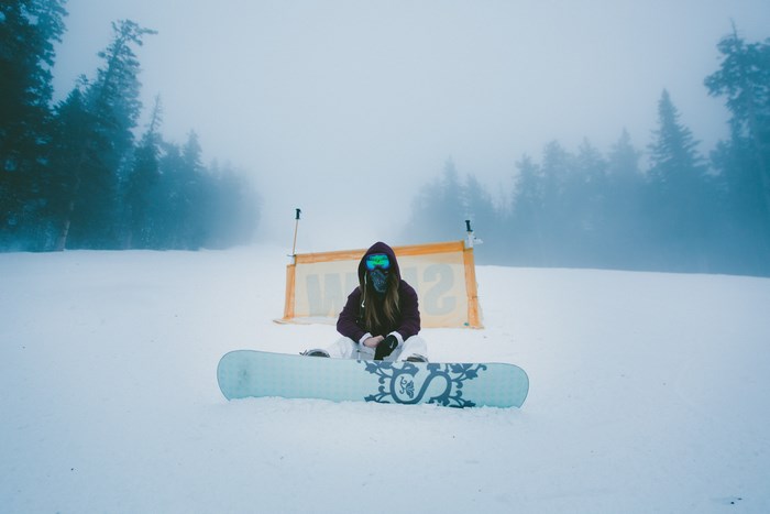 Woman sitting on a snowboard in the fog