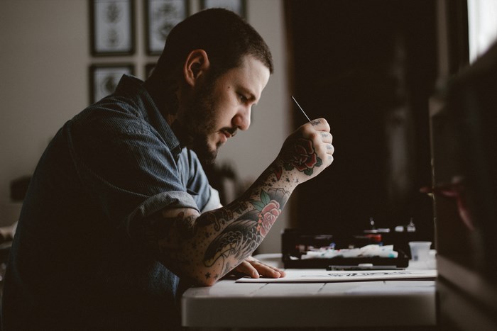 Tattoo artist drawing with a needle