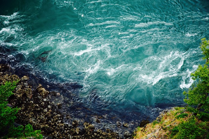Turquoise Water Rushing Past Rocky Shoreline