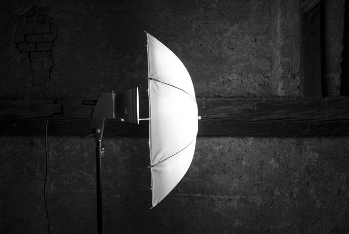Studio flash with white umbrella against brick wall