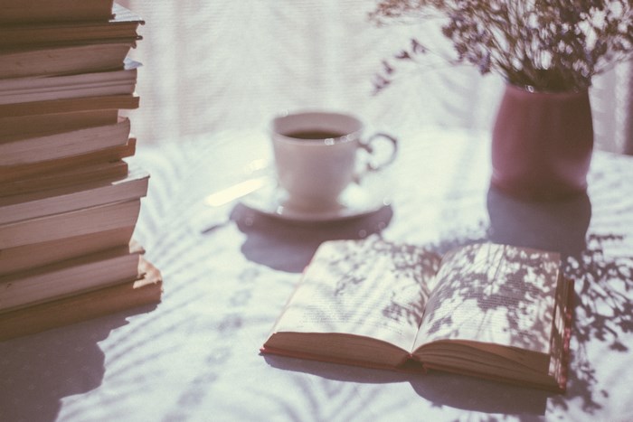 Stack of books, coffee cup, and vase with flowers
