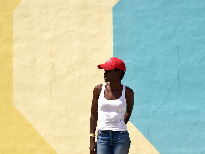 Woman in red cap and white vest against colorful wall