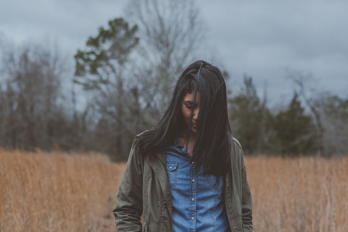 Woman in a field with trees and overcast sky