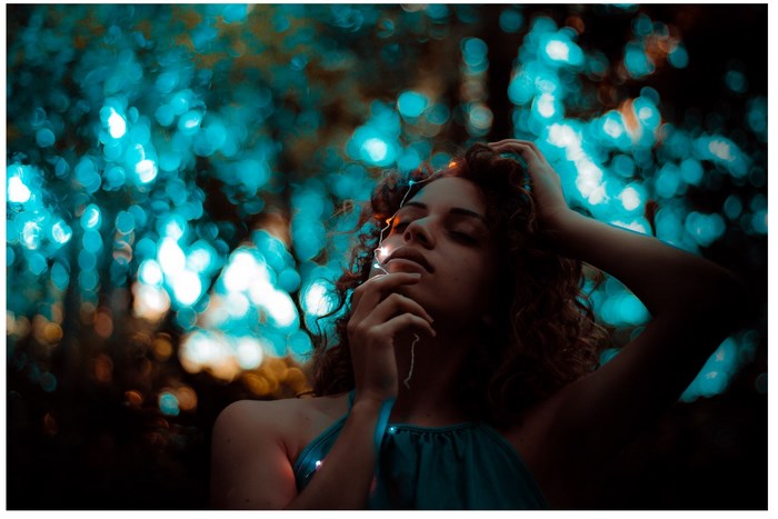 Woman with fairy lights in a bokeh forest