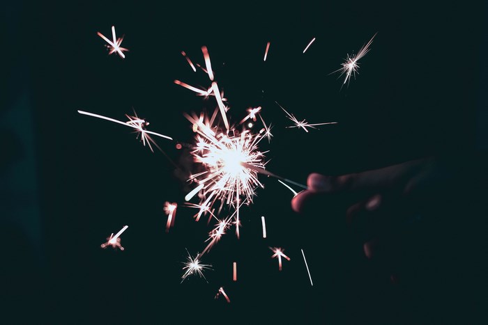Hand holding a sparkler with glowing sparks