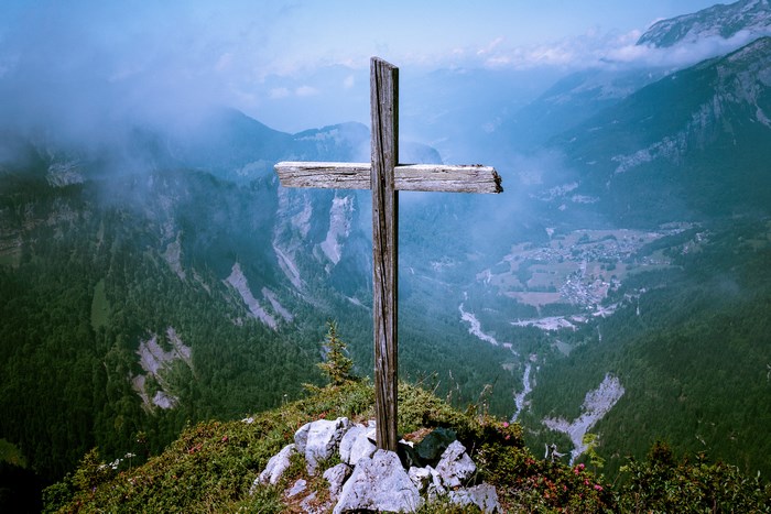 Wooden cross on a mountain summit overlooking a valley