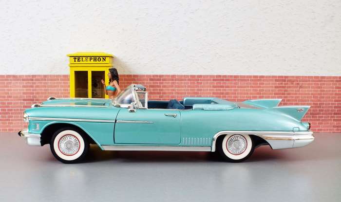 Model Cadillac Eldorado convertible with woman by telephone booth