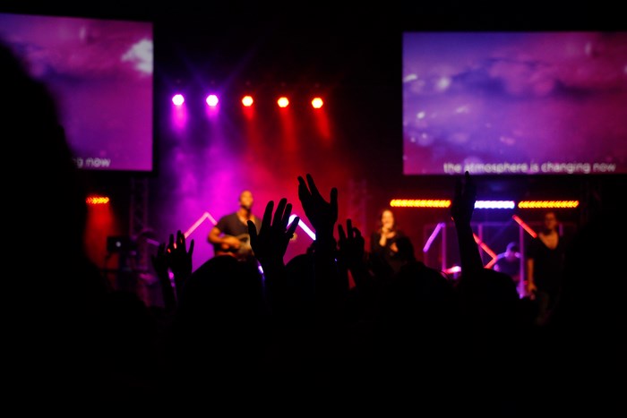People worshiping at a concert with screens and lights