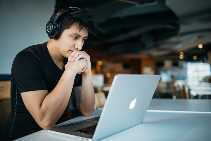 Man wearing headphones using a MacBook laptop