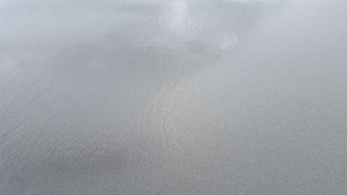 Wet sand with reflections on the seashore