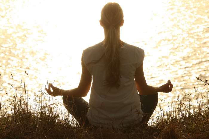 Woman meditating at sunset